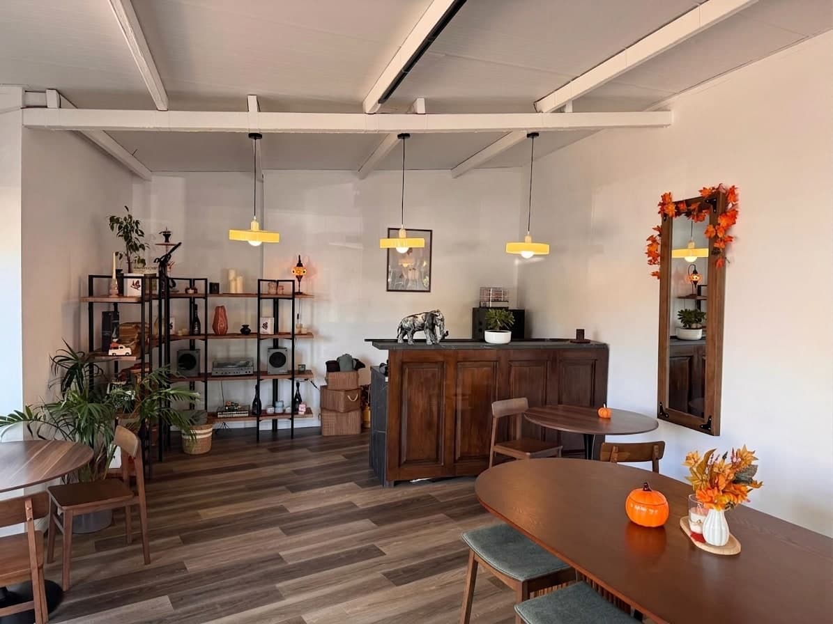 The room: open shelves of candles, books and a turntable, the wooden back bar, yellow pendant lamps and tables.